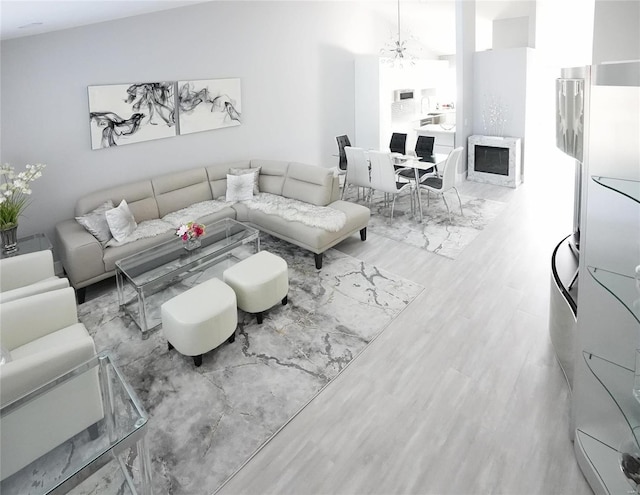 living room featuring an inviting chandelier, a fireplace, and light hardwood / wood-style floors