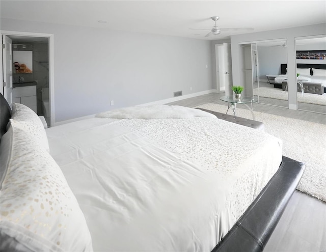 bedroom featuring ceiling fan, light hardwood / wood-style floors, and two closets