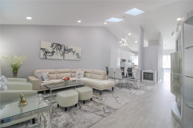 living room featuring hardwood / wood-style floors, an inviting chandelier, high vaulted ceiling, and a skylight