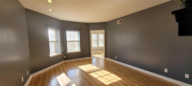 unfurnished room featuring a baseboard heating unit and light hardwood / wood-style flooring