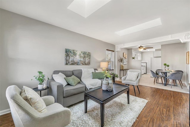 living room with hardwood / wood-style flooring, ceiling fan, and a skylight