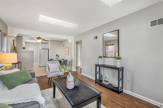 living room with hardwood / wood-style flooring, a skylight, and a wealth of natural light