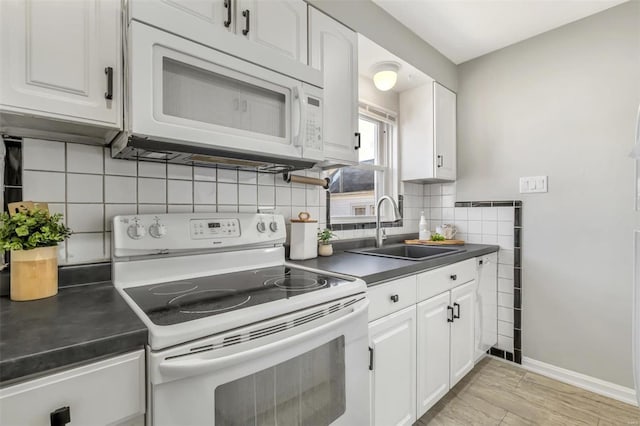 kitchen with tasteful backsplash, sink, white cabinets, light hardwood / wood-style floors, and white appliances