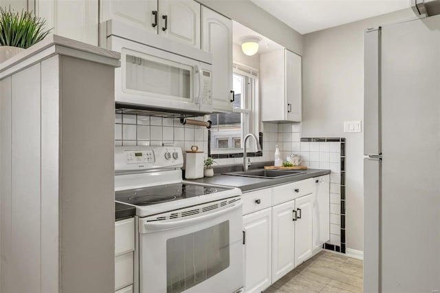 kitchen featuring sink, white appliances, tasteful backsplash, light hardwood / wood-style floors, and white cabinets