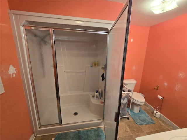 bathroom featuring tile patterned flooring, toilet, and a shower with shower door