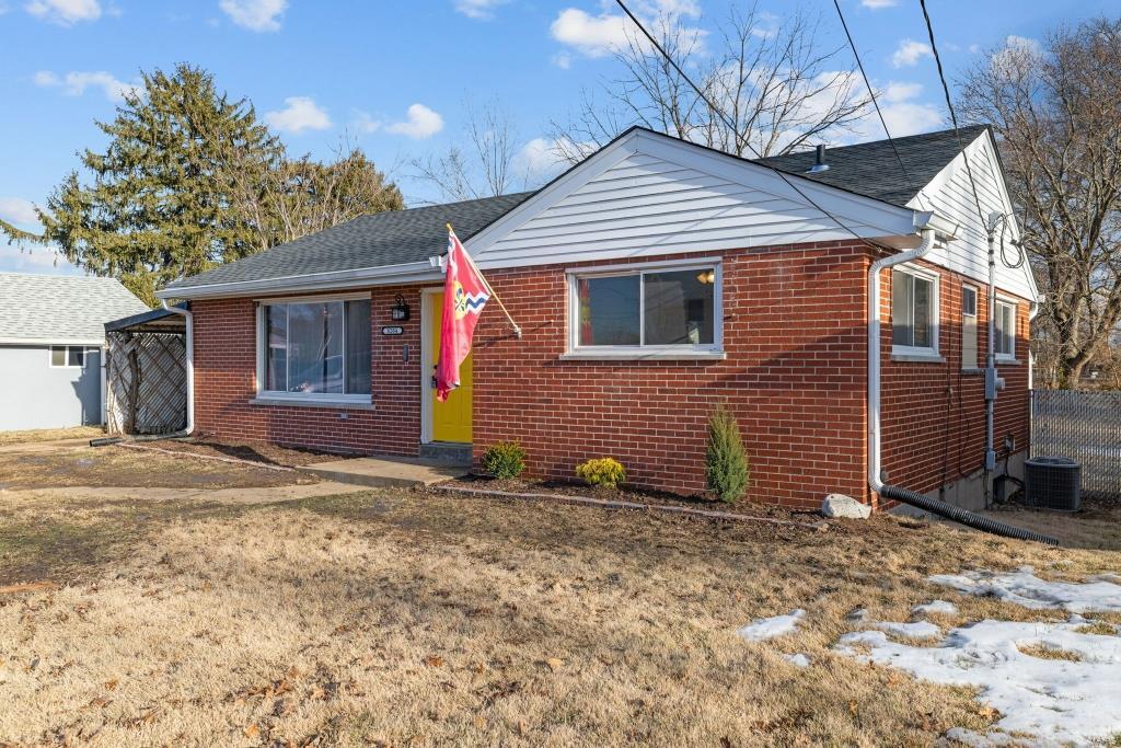 bungalow-style house featuring central AC unit and a front lawn