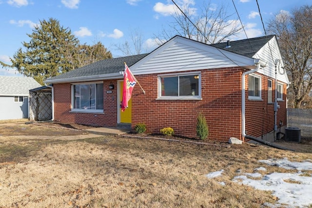 bungalow-style house featuring central AC unit and a front lawn