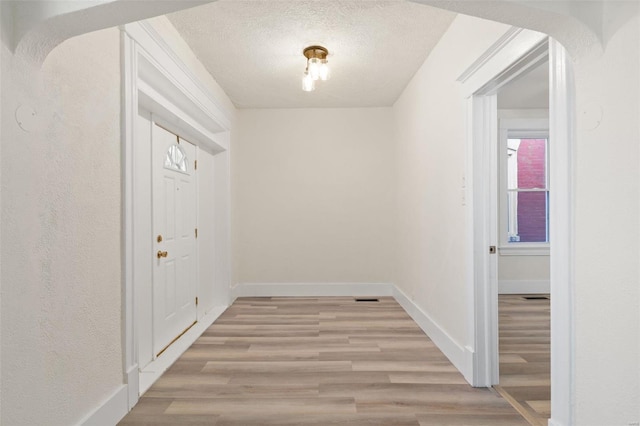 hallway with a textured ceiling and light wood-type flooring