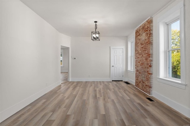 unfurnished dining area with a healthy amount of sunlight, a chandelier, and light wood-type flooring