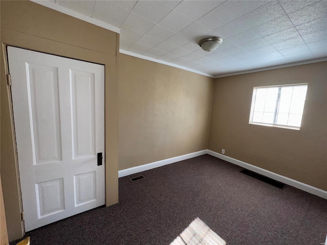 unfurnished room featuring crown molding and dark colored carpet