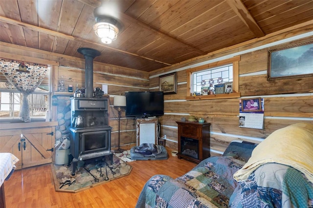 living room with a wealth of natural light, hardwood / wood-style floors, wooden walls, a wood stove, and wooden ceiling