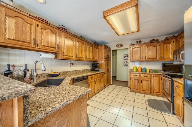 kitchen with sink, appliances with stainless steel finishes, backsplash, light stone countertops, and light tile patterned flooring