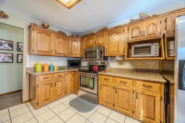 kitchen with backsplash, light tile patterned floors, and appliances with stainless steel finishes