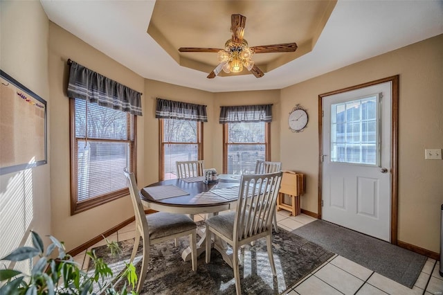 dining area with a healthy amount of sunlight, a raised ceiling, and light tile patterned floors