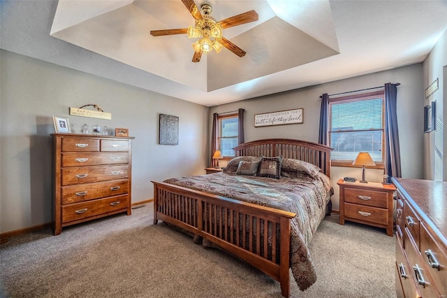 bedroom with ceiling fan, a raised ceiling, light carpet, and multiple windows