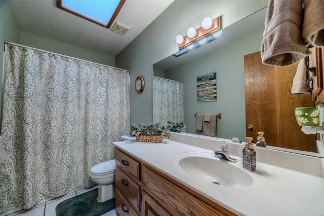 bathroom with vanity, a skylight, tile patterned floors, and toilet