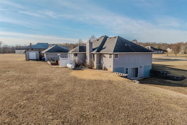 back of property with a garage, central AC unit, and a lawn