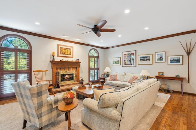 living room featuring ornamental molding, a healthy amount of sunlight, a fireplace, and light hardwood / wood-style floors