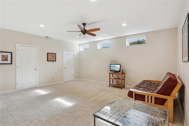 living area featuring ceiling fan, plenty of natural light, and light carpet