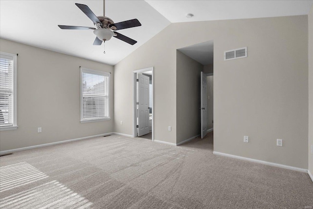 empty room featuring ceiling fan, light colored carpet, lofted ceiling, and a wealth of natural light