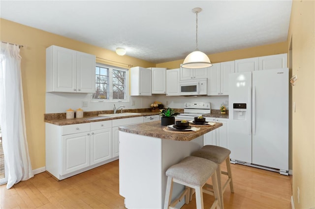 kitchen with white cabinetry, white appliances, pendant lighting, and a kitchen island