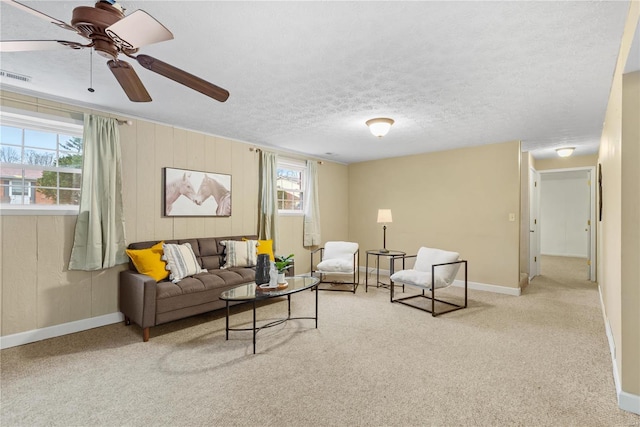 carpeted living room featuring ceiling fan, a textured ceiling, and wood walls