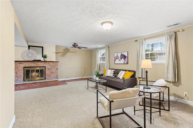 living room featuring a fireplace, a textured ceiling, carpet, and a wealth of natural light