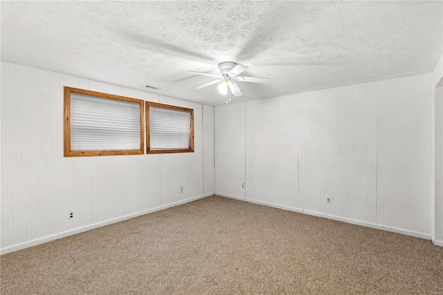 carpeted spare room featuring a textured ceiling and ceiling fan