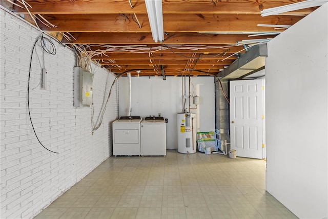 basement featuring separate washer and dryer, electric panel, electric water heater, and brick wall