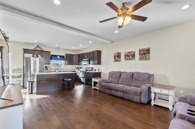 living room featuring dark hardwood / wood-style flooring, sink, beam ceiling, and ceiling fan