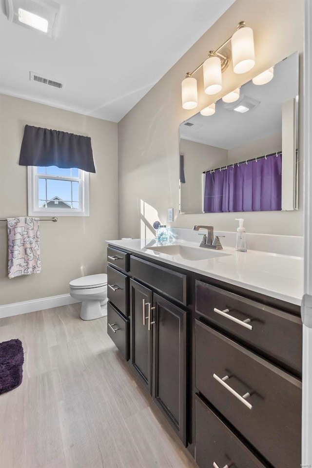 bathroom featuring vanity, wood-type flooring, and toilet