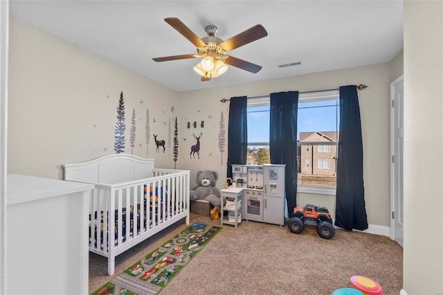 carpeted bedroom with a nursery area and ceiling fan