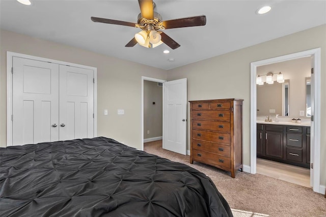 carpeted bedroom featuring sink, ensuite bath, a closet, and ceiling fan