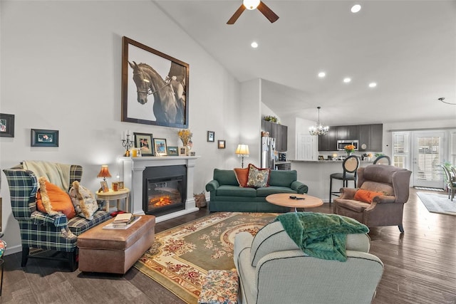 living room with wood-type flooring, lofted ceiling, and ceiling fan with notable chandelier