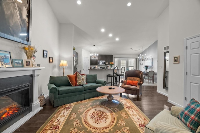 living room with dark wood-type flooring, high vaulted ceiling, and a notable chandelier