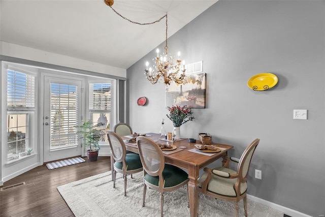 dining room with vaulted ceiling, dark wood-type flooring, and an inviting chandelier