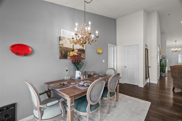 dining room featuring dark hardwood / wood-style floors, a chandelier, and a high ceiling