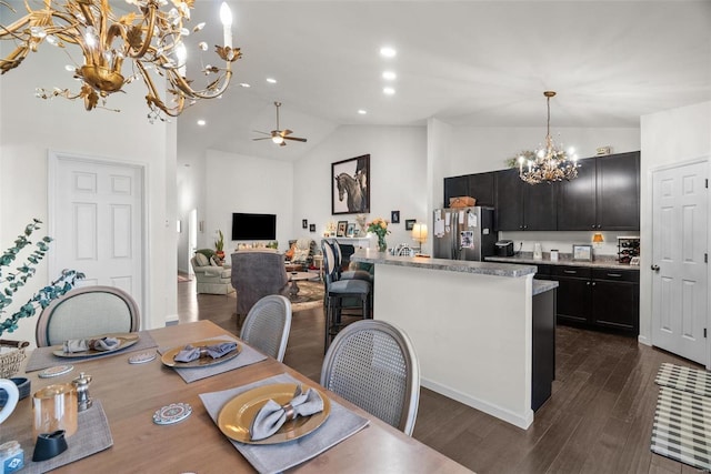 dining space with dark hardwood / wood-style flooring, ceiling fan with notable chandelier, and high vaulted ceiling