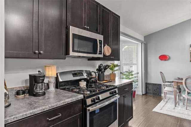 kitchen featuring dark brown cabinetry, appliances with stainless steel finishes, and dark hardwood / wood-style floors