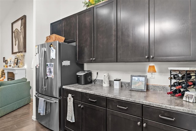 kitchen featuring dark brown cabinetry, hardwood / wood-style flooring, and stainless steel refrigerator