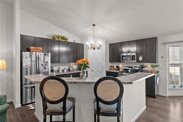 kitchen with a kitchen island, decorative light fixtures, a kitchen breakfast bar, dark hardwood / wood-style flooring, and stainless steel appliances