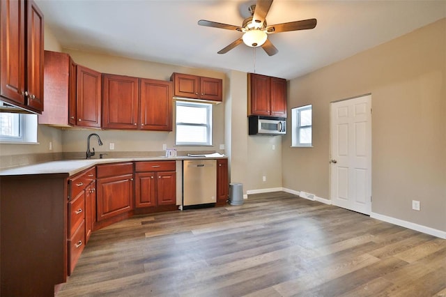 kitchen with hardwood / wood-style flooring, ceiling fan, sink, and stainless steel appliances