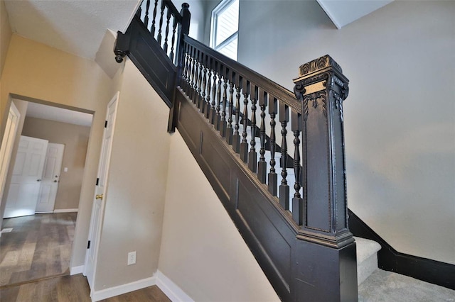 staircase with hardwood / wood-style flooring and a towering ceiling