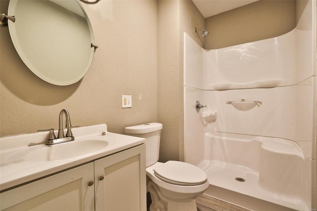 bathroom with toilet, vanity, and walk in shower