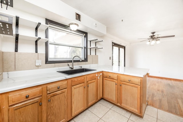 kitchen featuring light tile patterned flooring, ceiling fan, kitchen peninsula, and sink