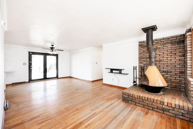 living room with light hardwood / wood-style flooring, ceiling fan, and a wood stove