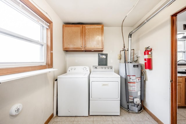 clothes washing area with light tile patterned floors, water heater, cabinets, and separate washer and dryer