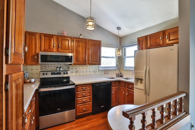 kitchen with sink, vaulted ceiling, dark hardwood / wood-style floors, pendant lighting, and stainless steel appliances