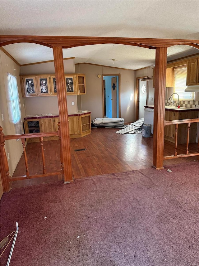 unfurnished living room with lofted ceiling, crown molding, carpet floors, and a textured ceiling