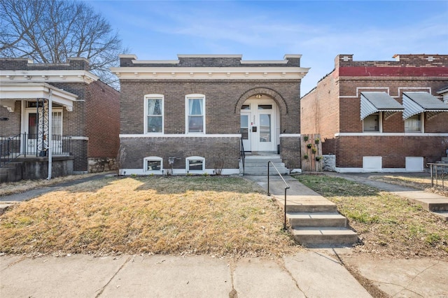 view of front of property with brick siding, french doors, and a front lawn